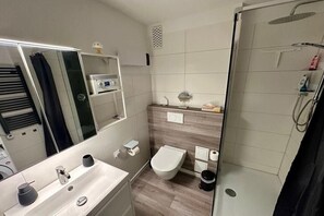 Een moderne badkamer met toilet, wastafel en douche.
