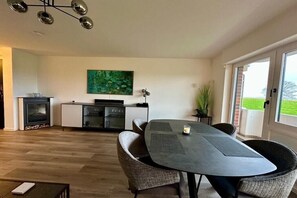Een eetruimte met een tafel, stoelen, een open haard, een kast en een schilderij aan de muur.
