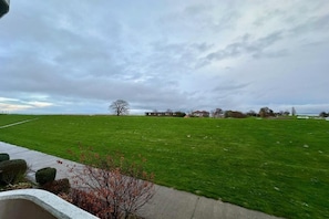 A large green field with a building in the distance and a clear sky. - LEEV Wo 12, Schillig Hörn. 2, Schillig (Schillig)