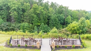 An outdoor deck with seating and a pathway leading to it, surrounded by dense greenery. - Gatlinburg | Romantic Smoky Mountain Escape | Trails + Pool (Gatlinburg)