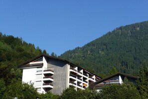 A multi-story hotel with balconies, set against a backdrop of a forested mountain. - Holiday apartment in Berchtesgaden with Wi-Fi (Berchtesgaden)