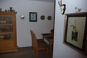 A dining area with a wooden table and chairs, a cabinet with dishes, and a framed picture on the wall. - Holiday apartment in Berchtesgaden with Wi-Fi (Berchtesgaden)