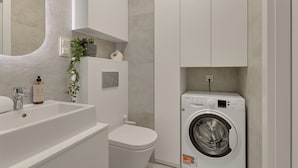 Un baño moderno con lavamanos blanco, inodoro y lavadora integrada.