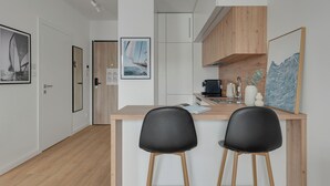 Cocina moderna con encimera de madera, dos sillas negras y una cafetera.