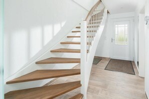 Eine Treppe mit Holzboden und weißen Geländern, die zu einer Tür führt.