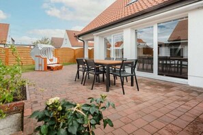 Ein Patio mit Tisch und Stühlen, umgeben von einem Pflasterboden und Holzzäunen.