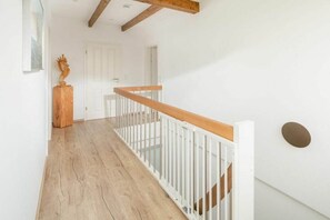 Ein Korridor mit Holzboden, weißen Wänden und einer weißen Geländer.