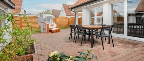 A patio area with a table and chairs, a covered seating area, and a view of neighboring houses.