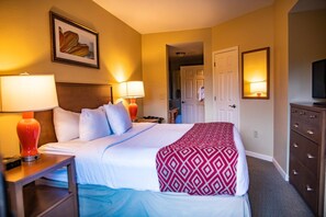 A hotel room with a bed, two bedside lamps, a dresser, a television, and a framed picture on the wall. - Pigeon Forge | Romantic Mountain Retreat | Trails + Attractions (Pigeon Forge)