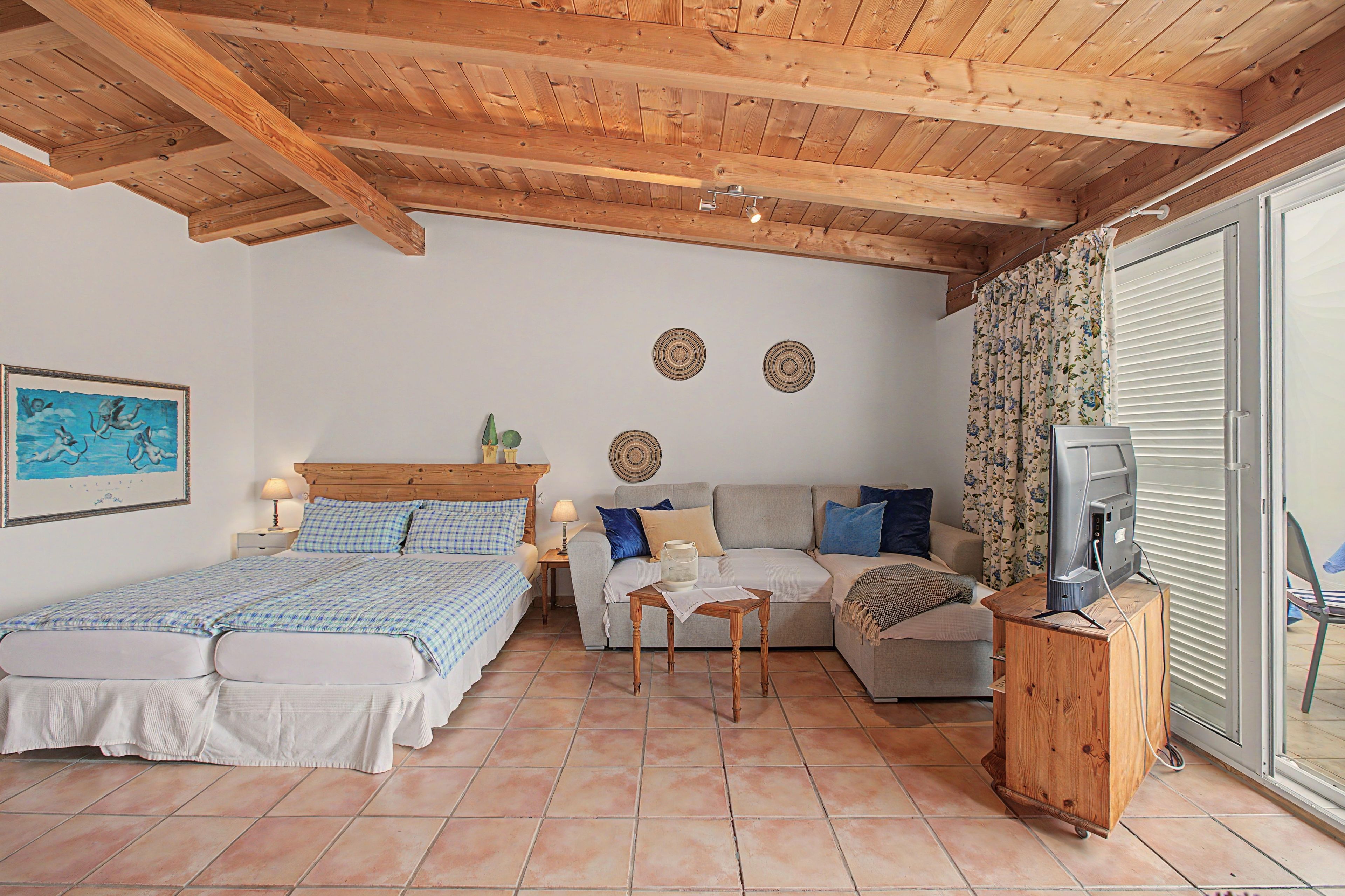 Une chambre à coucher avec un lit, un canapé, une télévision et une table.