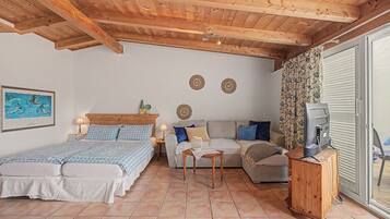 Une chambre à coucher avec un lit, un canapé, une télévision et une table.