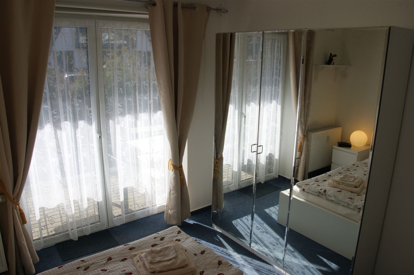 Ein Schlafzimmer mit einem Bett, einem Nachttisch, einer Lampe und einem großen Spiegel.