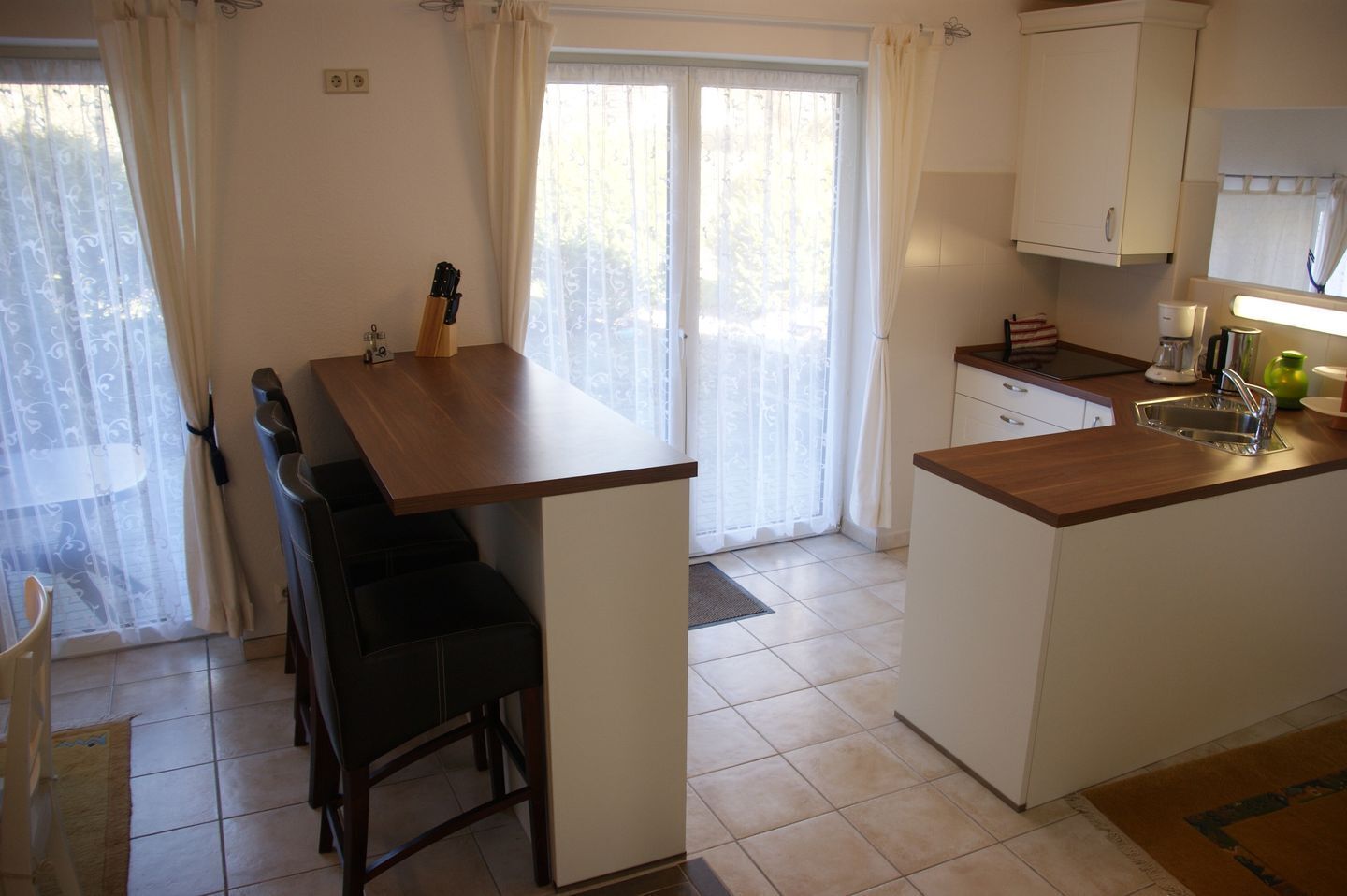 Una cocina compacta con comedor, un lavamanos y una ventana con cortinas.