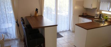 Una cocina compacta con comedor, un lavamanos y una ventana con cortinas.