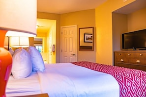 A hotel room with a bed, a television, a dresser, and a door. - Pigeon Forge | Smoky Mountain Villa | Spa + Pool (Pigeon Forge)