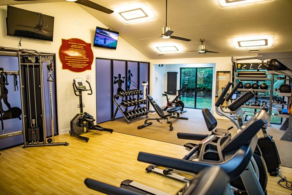 A gym with exercise equipment, a television, and a large window.