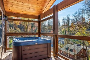 Een houten terras met een jacuzzi, houten leuningen en uitzicht op herfstkleuren.