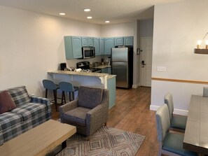 A compact living space with a kitchenette, a sofa, a chair, and a dining area. - Boyne Falls | Family Mountain Break | Skiing + Trails | 2BR (Boyne Falls)