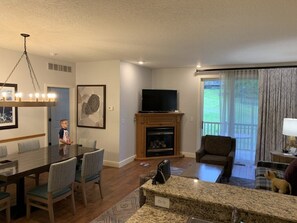 A living room with a fireplace, television, dining table, and chairs. - Boyne Falls | Family Mountain Break | Skiing + Trails | 2BR (Boyne Falls)