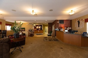 A hotel lobby with a reception desk, a large American flag, and a reception area with a counter and chairs. - Boyne Falls | Family Mountain Break | Skiing + Trails | 2BR (Boyne Falls)