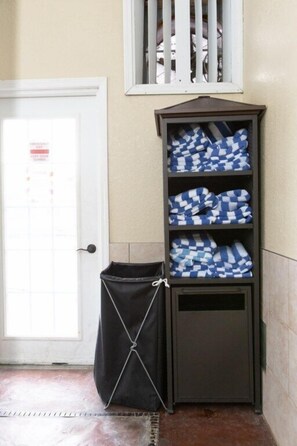 A corner storage unit with folded blankets, a door with a calendar, and a window with blinds. - Boyne Falls | Family Mountain Break | Skiing + Trails | 2BR (Boyne Falls)