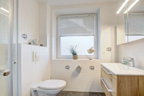 Un baño moderno con inodoro, lavamanos y ventana.