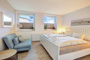 Un dormitorio con cama, sofá y dos ventanas con persianas.