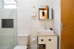 A modern bathroom with a toilet, sink, mirror, and wooden door. - Modern in Cond. w/ Parking at Rio Tavares Ala0004 (Florianópolis)