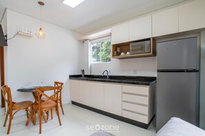 A modern kitchen with a dining area, built-in microwave, and a refrigerator. - Modern in Condo w/ Parking in Rio Tavares Ala0001 (Florianópolis)