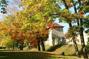 A stone building with a red-tiled roof, surrounded by trees with autumn foliage. - Holiday apartment Assenta (Blankenburg)