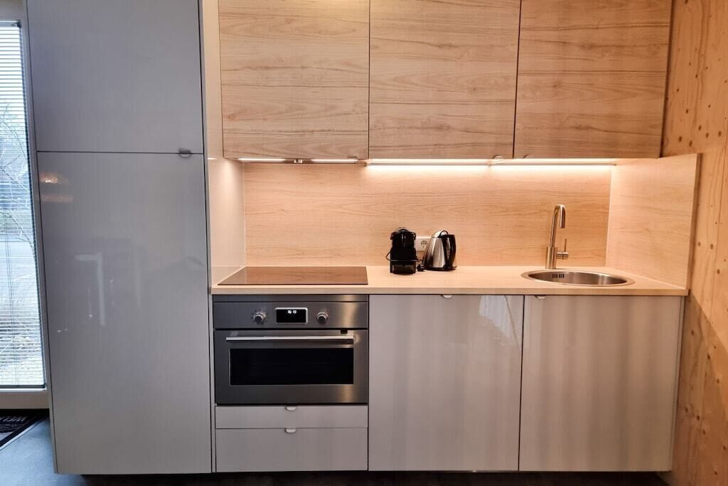 Una cocina moderna con horno de acero inoxidable, cafetera y lavamanos.