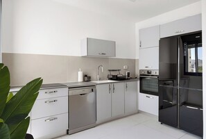 A modern kitchen with stainless steel appliances, a dishwasher, and a refrigerator. - Cozy & Spacious 3BR with Balcony & Mamad (Bat Yam)