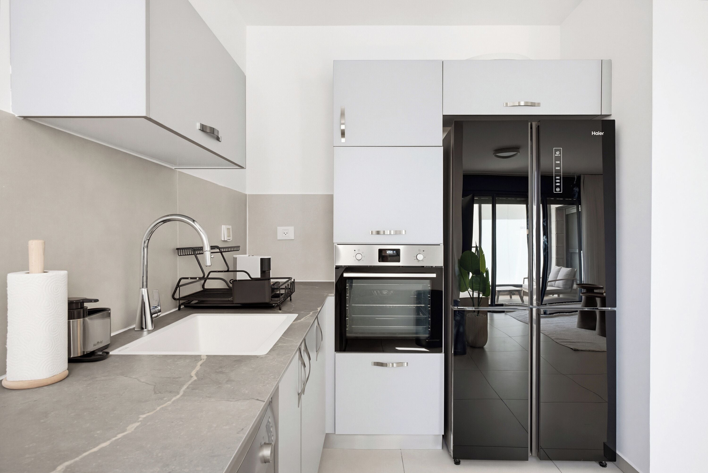 A modern kitchen with a built-in oven, a stainless steel refrigerator, and a sleek faucet.
