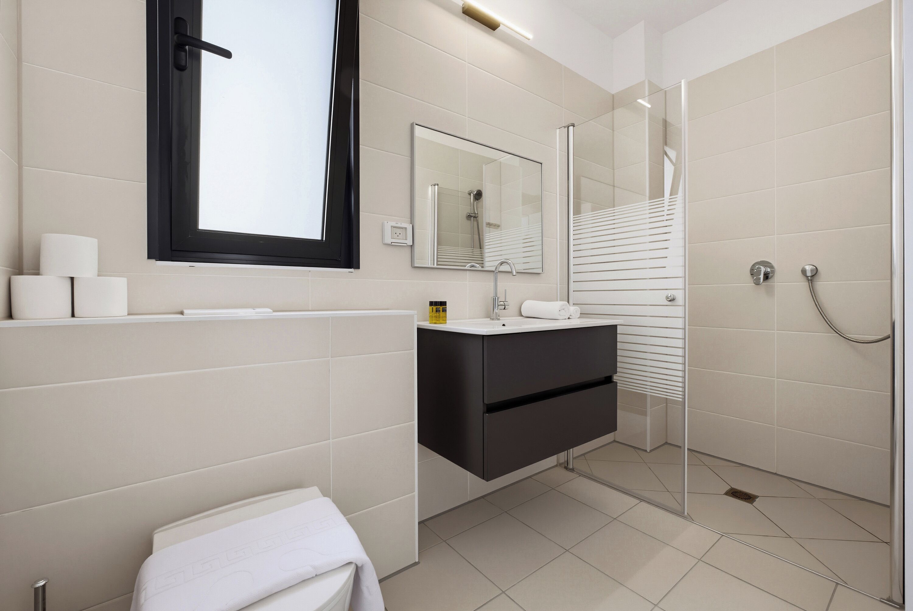 Un baño moderno con inodoro, lavamanos, espejo y ducha.