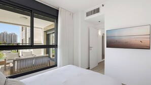Habitació d'hotel amb un llit, una finestra que mostra edificis, una porta i un quadre penjat a la paret.