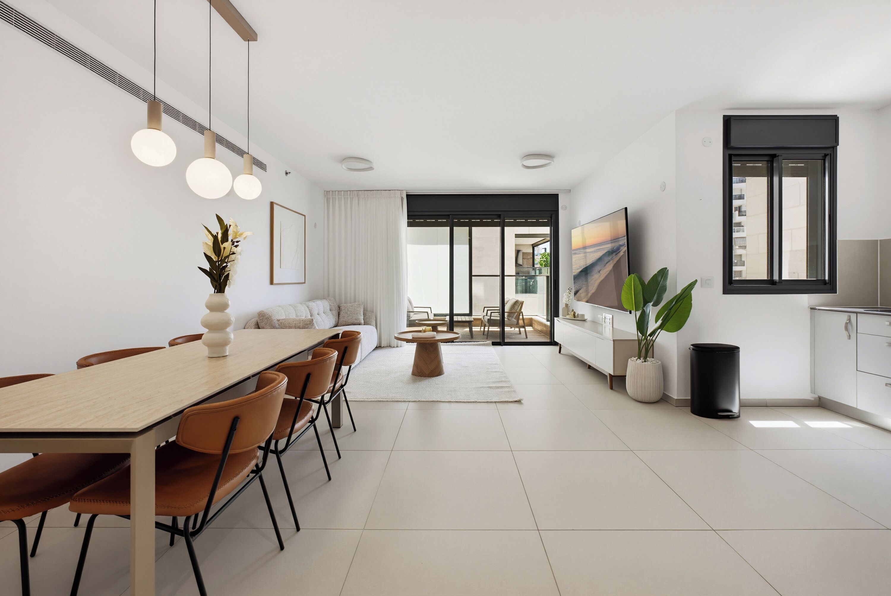 A modern living room with a dining area, a TV, and a large window.