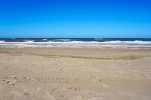 Ein Strand mit deutlichen Fußspuren und Wellen.