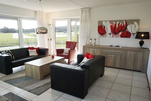 Ein modernes Wohnzimmer mit einer Sofagarnitur, einem Couchtisch und einem Essbereich mit Schrank und Lampe.