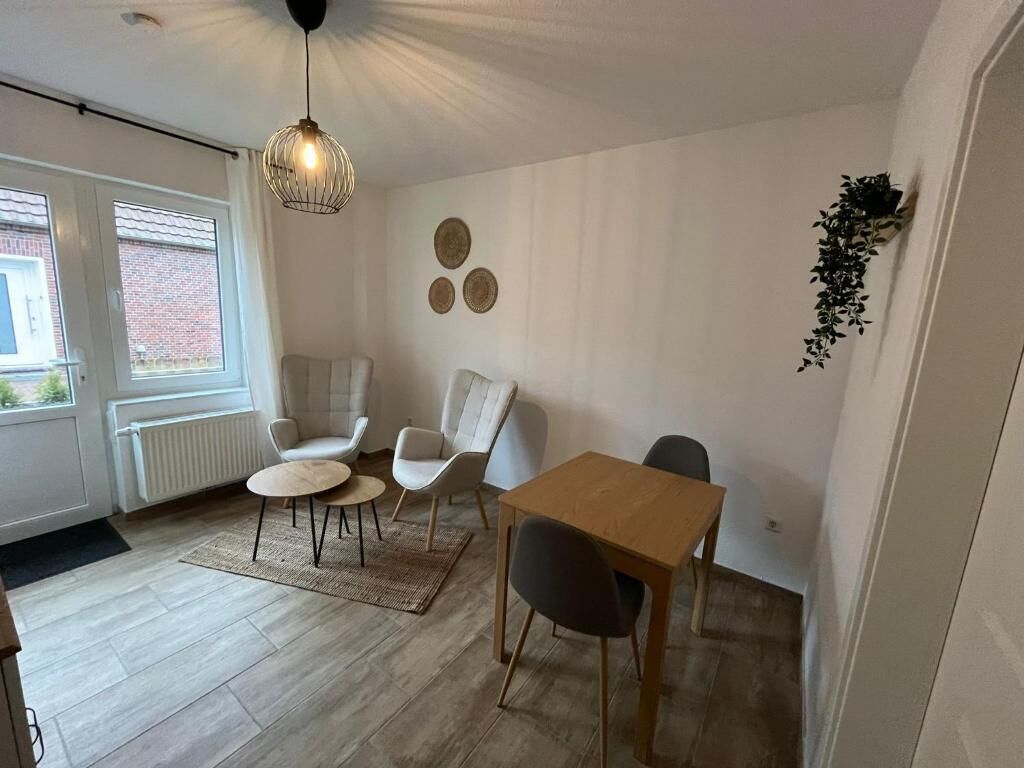 Ein Zimmer mit Esstisch, zwei Stühlen, einer Hängelampe und einer Heizung.