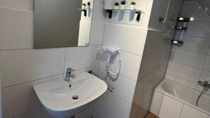 A modern bathroom with a white sink, mirror, and shower.