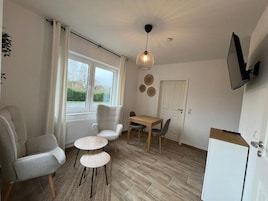 Eine moderne Küche mit Essbereich, inklusive Tisch, Stühlen, einem Kühlschrank und einem Fenster mit Vorhängen.