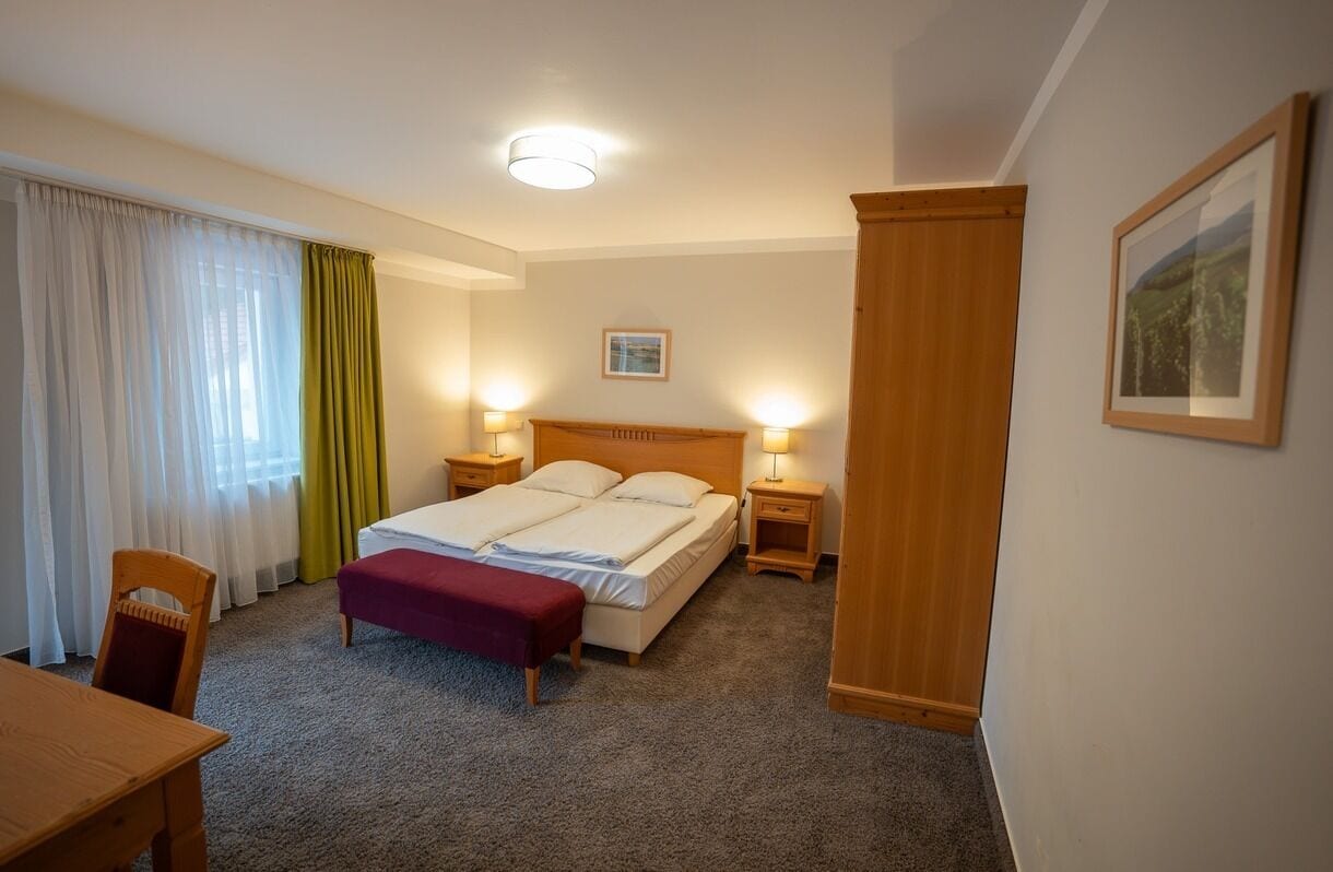 Une chambre d’hôtel avec un lit, des tables de chevet, une chaise, un bureau et un tableau au mur.