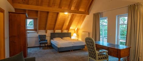 Une chambre avec un plafond en bois, un lit, un bureau, une chaise et une fenêtre.