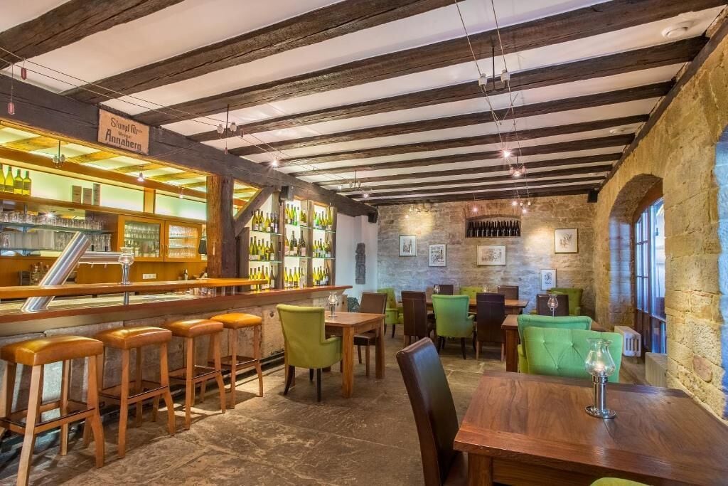 A bar area with stools, tables, and a stone wall.