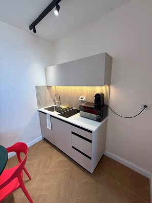 Une petite cuisine équipée d’un évier, d’une machine à café et d’un plan de travail.