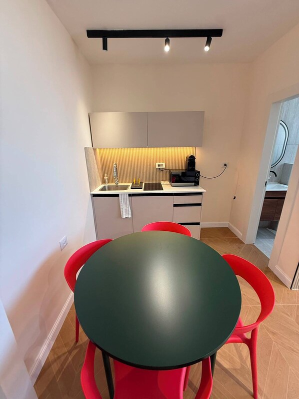 A compact kitchen with a dining area, including a table and chairs, a microwave, and a sink. - Prestigious Suite Near Mamilla—View of the Ancient Walls (Jerusalem)
