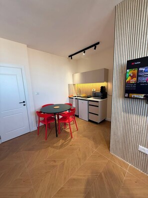 A compact kitchen with a microwave, toaster, and kettle, a dining area with a table and chairs, and a TV mounted on the wall. - Prestigious Suite Near Mamilla—View of the Ancient Walls (Jerusalem)