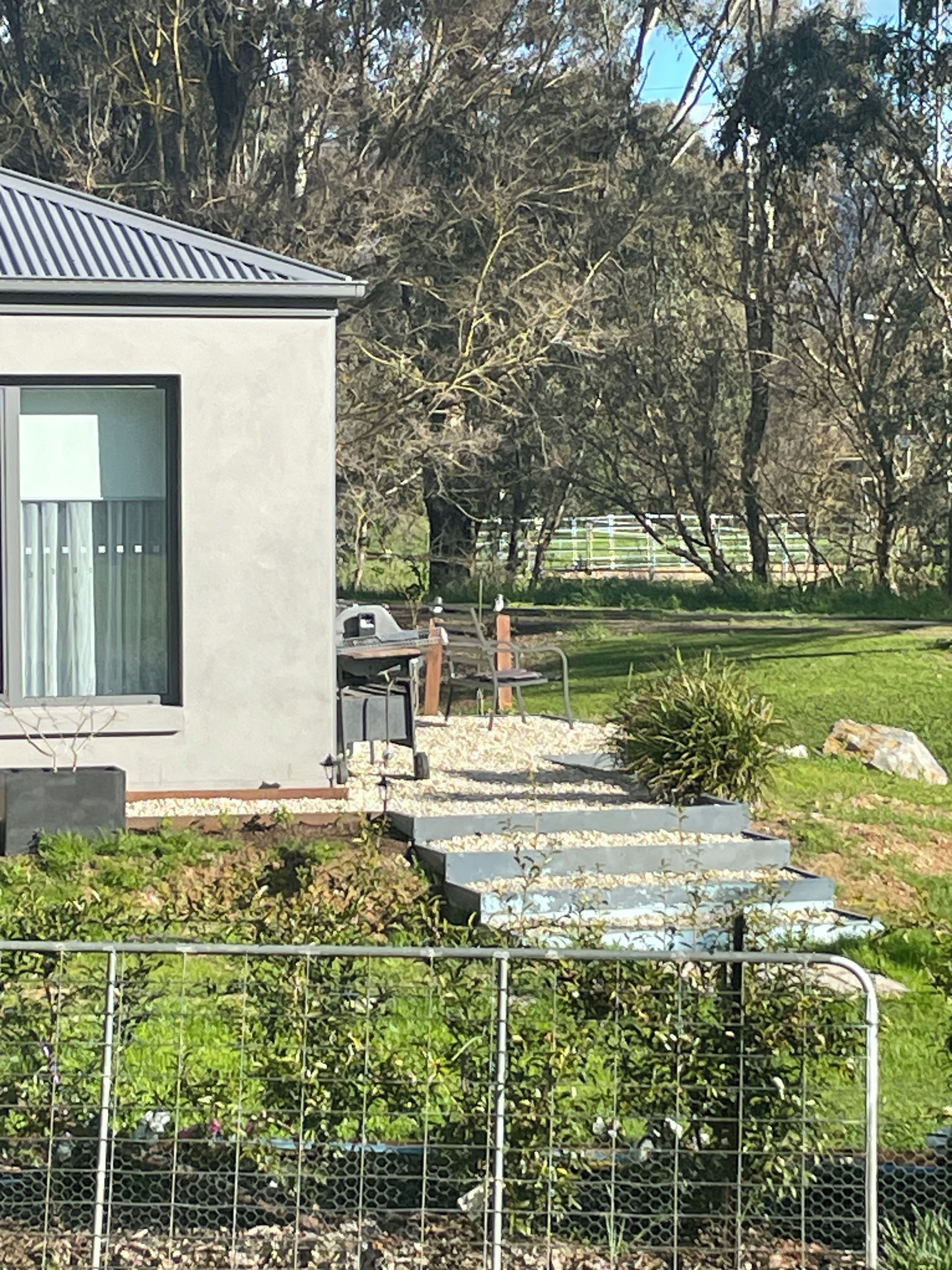 Un bâtiment moderne doté d’une grande fenêtre et d’un espace pavé menant à un banc.
