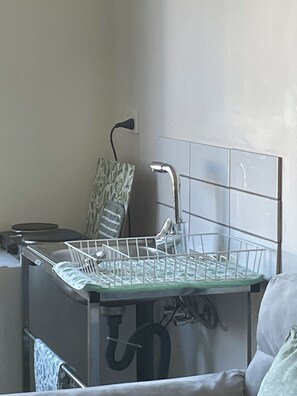 A compact kitchen area with a built-in dishwasher, a sink with a chrome faucet, and a towel rack.