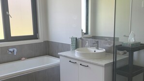 Et stilfuldt badeværelse med badekar, vask og et stort spejl.